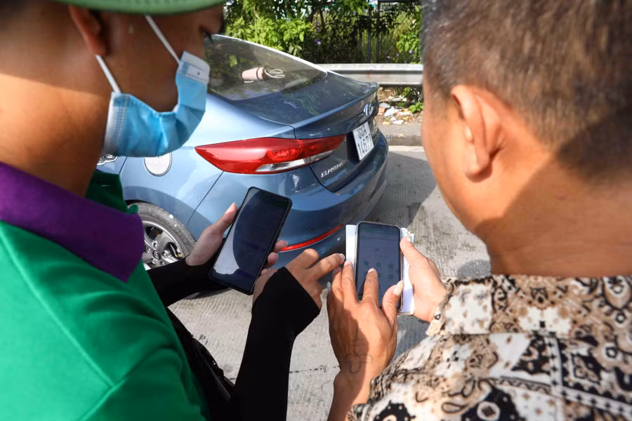 Nhân viên ETC dán thẻ và hướng dẫn các lái xe về cách nạp tiền vào tài khoản để đi vào làn không dừng.