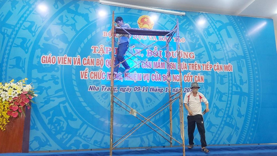 Thầy Đỗ Ánh Dương trực tiếp trên giàn giáo để thực hiện công việc treo phông chữ.