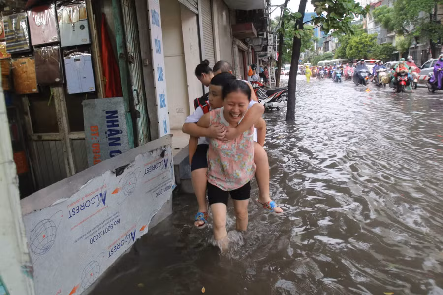 Mưa lớn vào buổi sáng, khiến nhiều người phải cõng con em mình đến trường học.