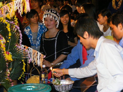 Tưng bừng tết Lào trên đất Việt ảnh 2 Các bạn sinh viên Lào thắp nến làm lễ buộc chỉ cổ tay