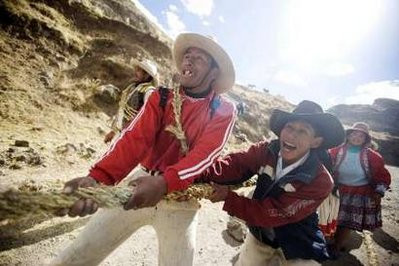 Andean men pull as they make ropes with a local grass to be used in the construction of the Qeswachaka hanging bridge
