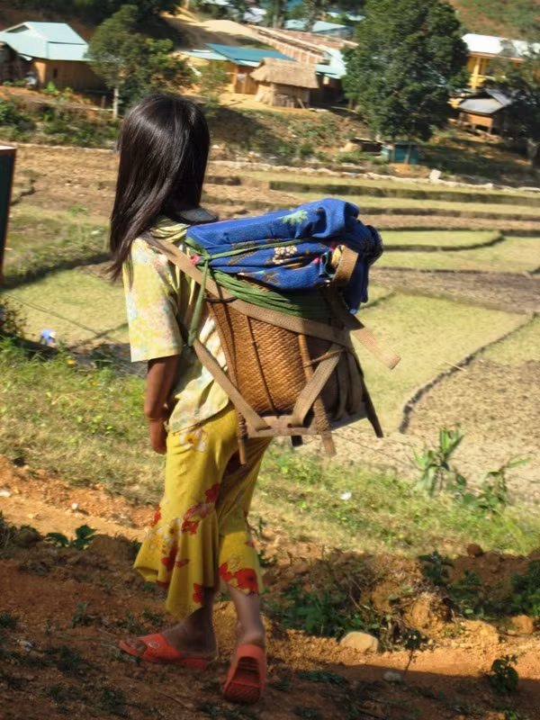 Bé CLâu thị Hái đang gồng mình gùi những gùi nặng nhọc sau lưng