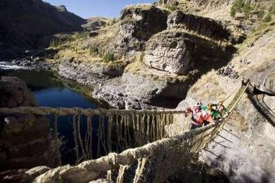 Andean men cross the Qeswachaka hanging bridge across the Apurimac river,