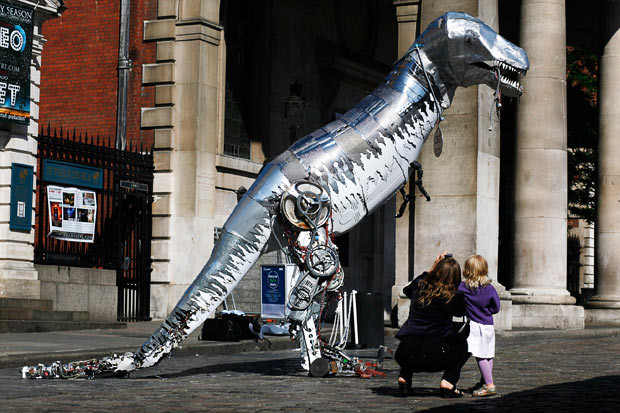 Những khoảnh khắc ấn tượng trong tuần ảnh 1 Karla 4, and her mum Laura Andersen from Denmark look at Tyrone the Recycled Rex, a 4 metre high dinosaur sculpture made entirely out of recycled domestic appliances as it is let loose in London’s Covent Garden by Indesit Company UK to mark the launch of Recycle Week