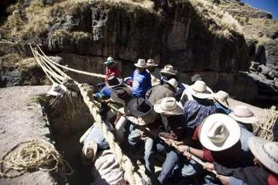 Andean men pull ropes made from a local grass as they build the Qeswachaka hanging bridge