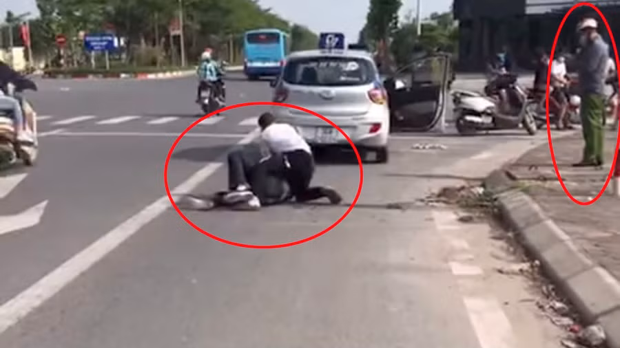 Anh Nguyễn Trần Minh vật lộn với tên cướp, trong khi người mặc quần xanh đứng bấm điện thoại. Ảnh cắt từ Clip