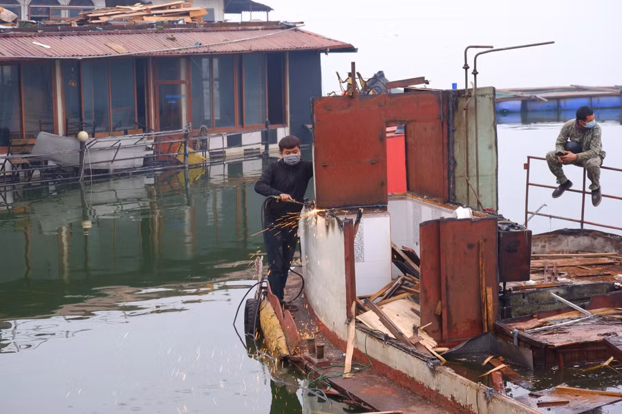 Công nhân sử dụng đèn khò dỡ tấm sắt trên các tàu thuyền.