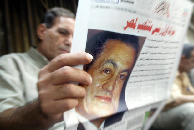 Sự nghiệp TT Ai Cập Hosni Mubarak qua ảnh ảnh 9 10 September 2005: A man reads a newspaper featuring a picture of Egyptian President Hosni Mubarak in Cairo one day after the presidential electoral commission announced official results giving Mubarak a whopping 88.5 percent of the vote, but with only 23 percent of registered voters turning out for the country’s first contested elections.