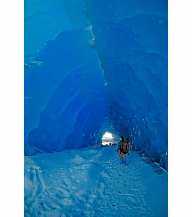 A man walks through a large ice tunnel formed by the shifting of icebergs along the terminus of the Mendenhall Glacier in Juneau, Alaska...