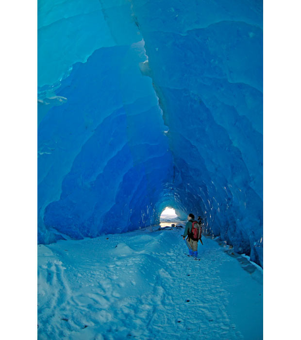 A man walks through a large ice tunnel formed by the shifting of icebergs along the terminus of the Mendenhall Glacier in Juneau, Alaska...