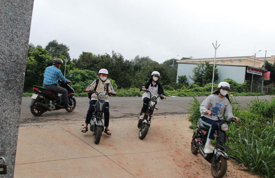 Một người đi xe máy ngược chiều buộc phải dừng lại để 3 em học sinh rẽ trái vào cổng trường. (Ảnh: TT).