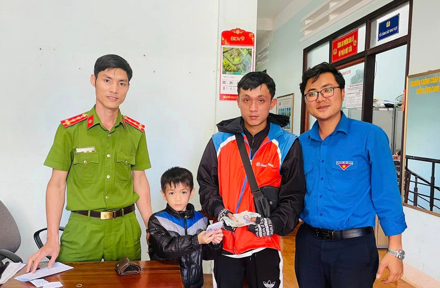 Em Hoàng Bảo Long trao trả lại chiếc ví cho người đánh rơi. (Ảnh: Công an phường Hoa Lư).