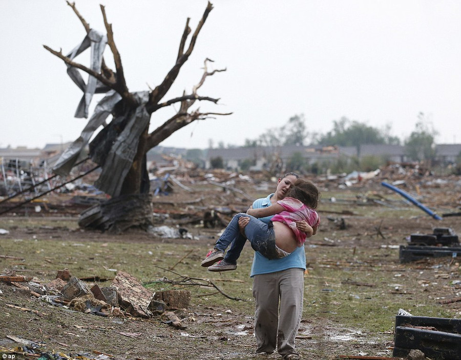 Devastation: A woman carries her child through a field near the collapsed Plaza Towers Elementary School in Moore, Oklahoma, today after the devastating tornado Read more: http://www.dailymail.co.uk/news/article-2328000/US-tornadoes-Yet-heartbreak-Oklahoma-massive-tornado-touches-highly-populated-suburb.html#ixzz2TtMFPKMo Follow us: @MailOnline on Twitter | DailyMail on Facebook