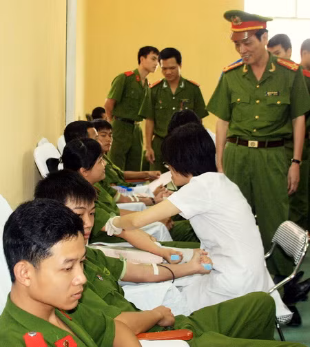 Phó hiệu trưởng Đoàn Việt Mạnh đang động viên học viên, chiến sĩ trong lúc lấy máu. Ảnh: gdtd.vn