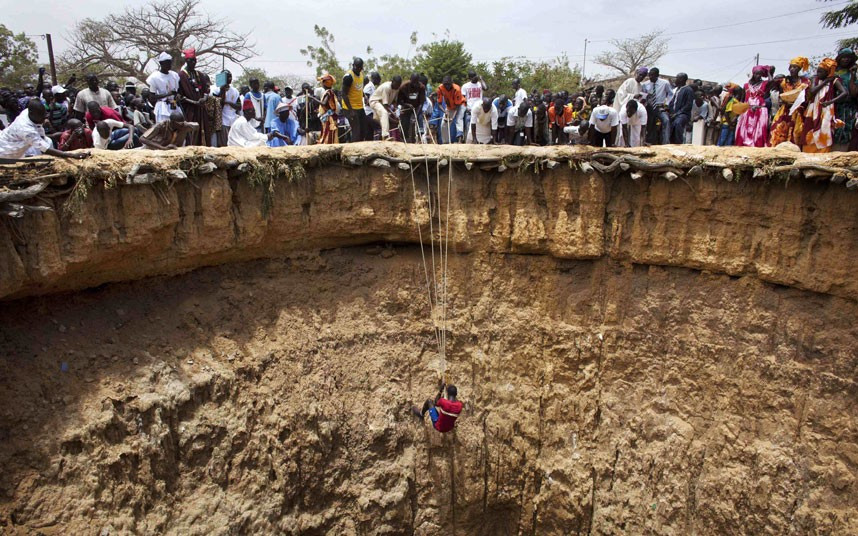 A man descends into a large former well during a traditional ceremony in the village of Ndande. Every year, inhabitants of the village take part in a Sufi Muslim ceremony called Gamou-Ndande. The ceremony combines nights of praying and chanting as well as traditionally animist ceremonies. The well, called Kalom, was the site of historic battles in Senegalese history. According to local historian Baye Niass, the well dates back to the 16th century. Today there is no water in the former well and it is used for ceremonial purposes. Niass says the well measure 36 meters in depth an 11m in diameter