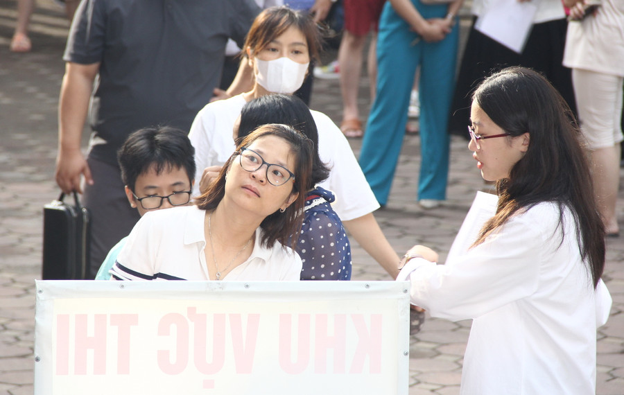 Phụ huynh này dõi theo con mình khi được sinh viên tình nguyện dẫn lên phòng thi.