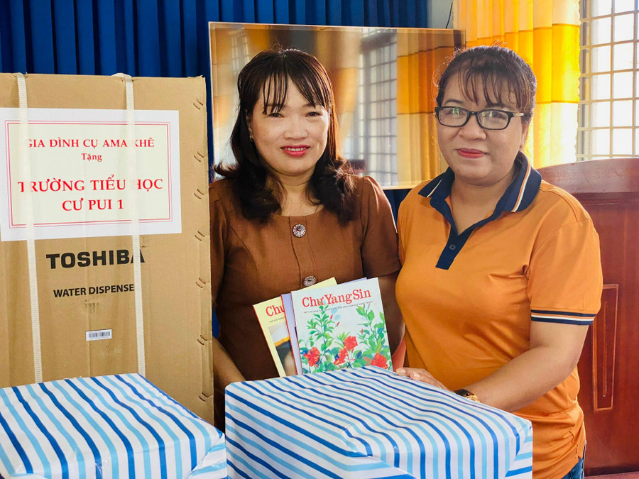 Nhà văn Niê Thanh Mai (bên phải) trao tặng tạp chí của Hội VHTN tỉnh cho đại diện Trường Tiểu học Cư Pui I.