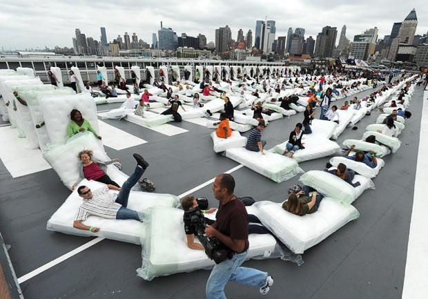 Volunteers attempt to break the Guinness World Record for human-mattress dominoes on the deck of the U.S.S. Intrepid, during the production of the morning show,