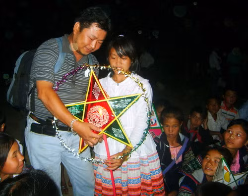 Cán bộ của cơ quan giúp đỡ xã chung vui với các em