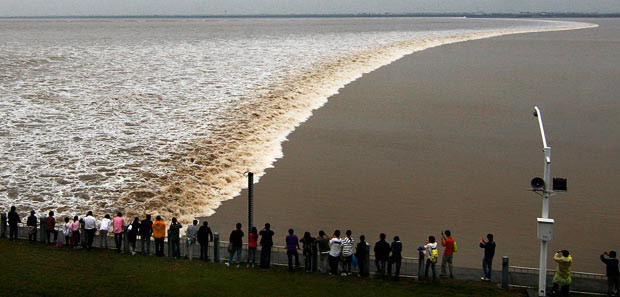 People watch a tidal wave during the autumnal equinox at Qiantangjiang River in Haining, Zhejiang Province of China