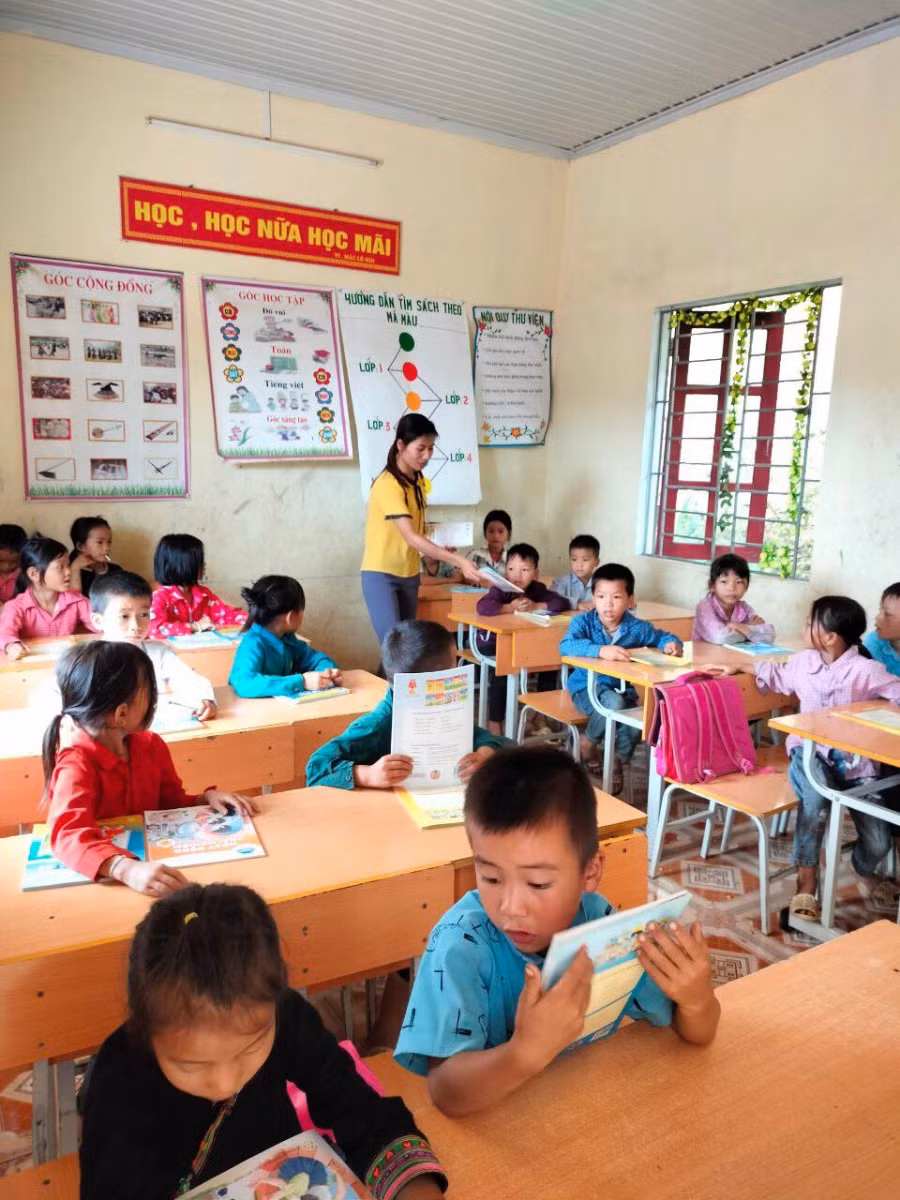 Giáo viên Trường PTDTBT Tiểu học Ngọc Long trao SGK vừa được trao tặng tới tay HS