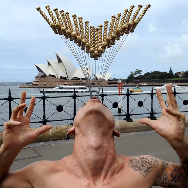 A street performer named Chayne Hultgren (aka The Space Cowboy), re-enacts his 18-sword swallowing attempt for a Guinness World Record in front of the Sydney Opera House