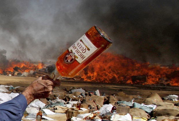 A Pakistani customs official prepares to destroy smuggled liquor during a ceremony to mark International Customs Day, in Karachi