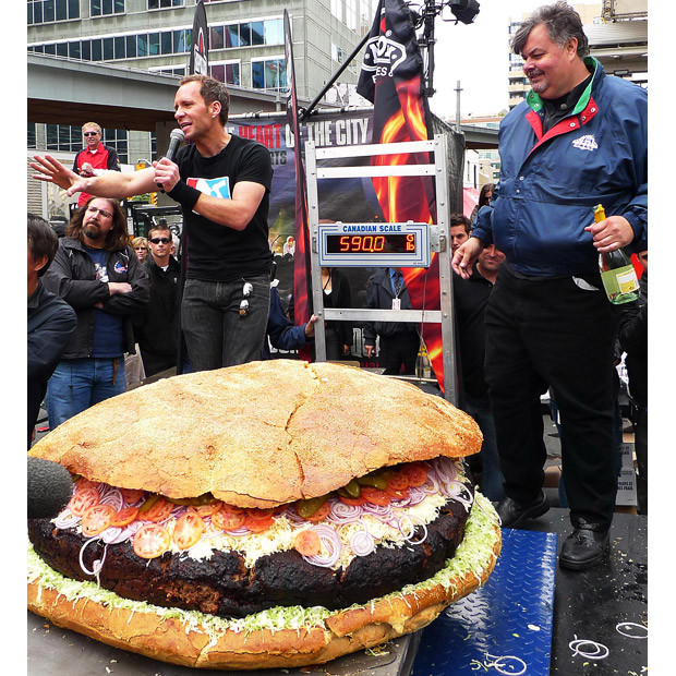 Chùm ảnh: Thế giới vui và lạ ảnh 5 Barbecue chef Ted Reader holds a bottle of champagne to celebrate the finish of a giant hamburger, weighing 590lb, in Toronto, Canada