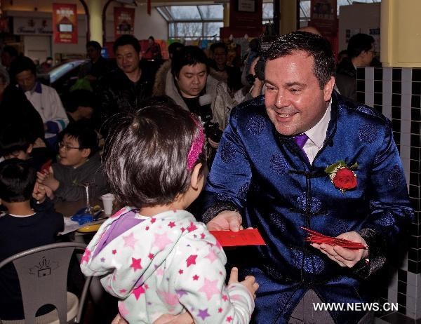 Canadian Minister of Citizenship, Immigration and Multiculturalism Jason Kenney (R) gives gift money to a girl during a New Year reception at an overseas Chinese community in Greater Toronto Area, Canada, on Jan. 29, 2011