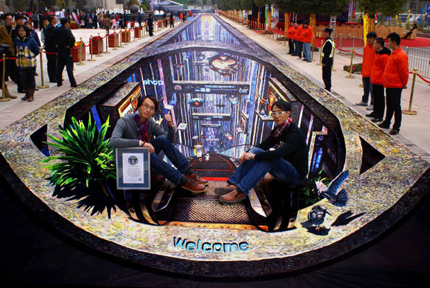 Brothers, Wan Yiju and Wan Yiheng, pose with their 148-metre-long 3D street painting, which sets a new Guinness record as the world’s longest 3D street painting, in Guangzhou, China