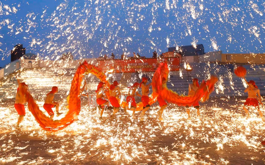 Dancers perform a fire dragon dance in a shower of molten iron during a performance to celebrate the Chinese Lunar New Year at an amusement park in Beijing