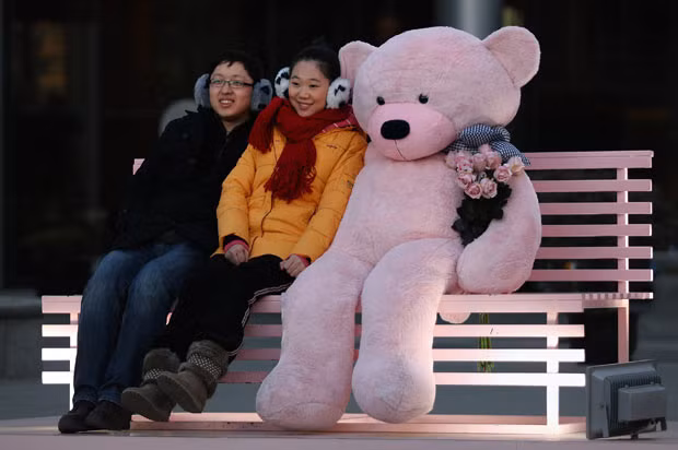 A couple have their picture taken with a giant teddy bear for Valentine’s Day outside a shopping mall in Beijing