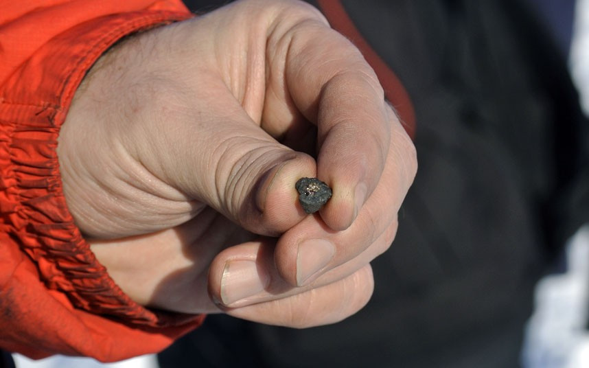 A man holds a meteorite fragment found near the Chebarkul Lake in Chelyabinsk Oblast, Russia