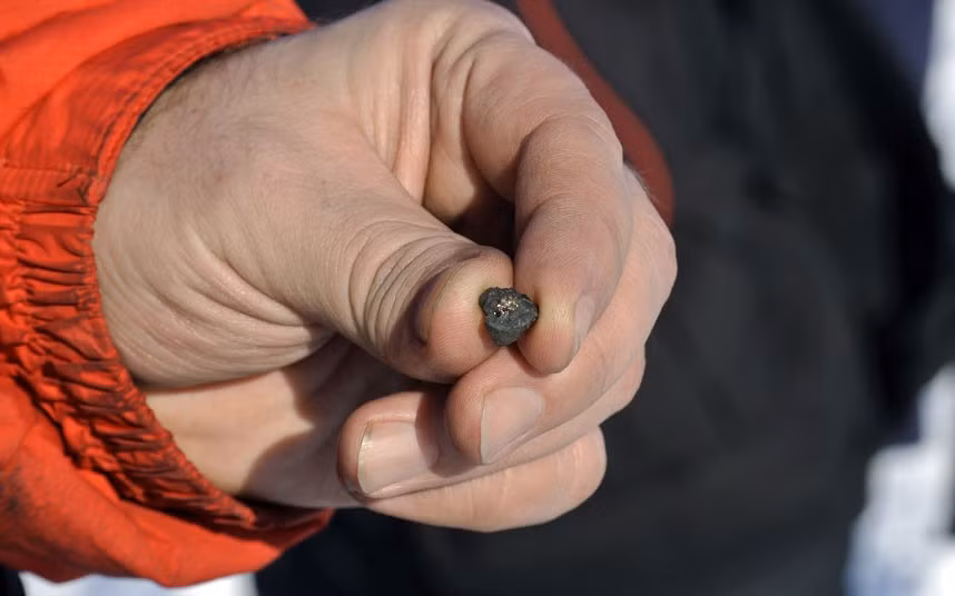 A man holds a meteorite fragment found near the Chebarkul Lake in Chelyabinsk Oblast, Russia