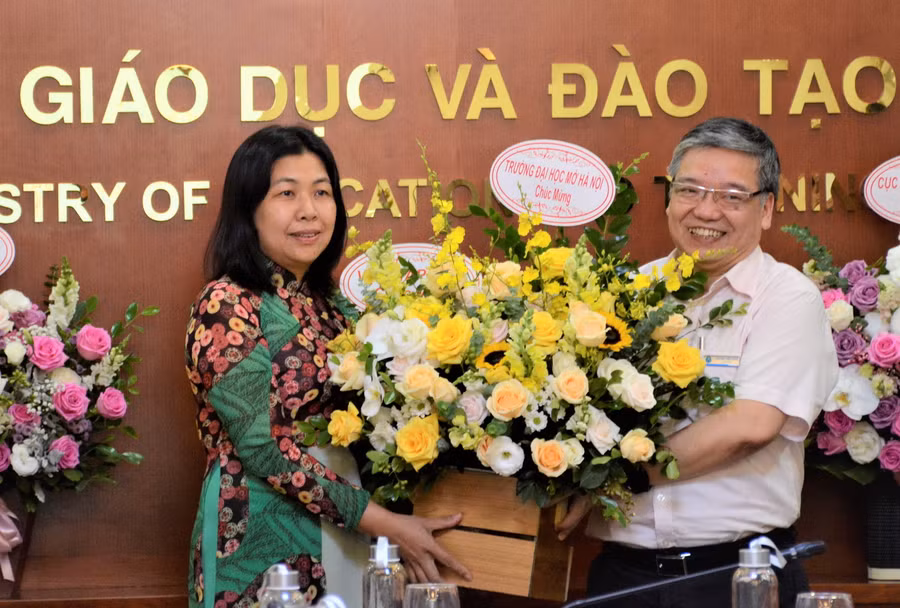 TS Trương Tiến Tùng - Hiệu trưởng Trường ĐH Mở Hà Nội tặng hoa chúc mừng tân Phó Vụ trưởng Vụ Giáo dục đại học