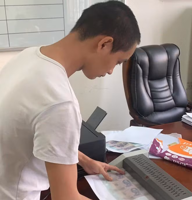 Phạm Văn Quang thao tác lại công đoạn làm tiền giả. Ảnh: Công an Hà Nội
