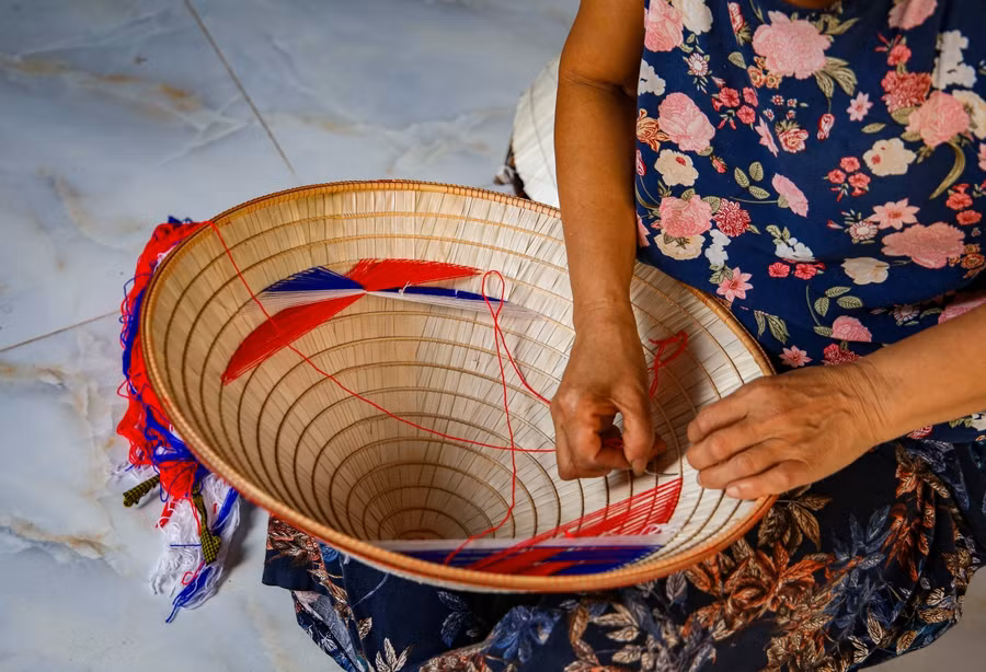 Cuối cùng người thợ sẽ dùng những sợi chỉ nhiều màu sắc như: đỏ, xanh, trắng…tiến hành lồng nhôi đối xứng, vừa là trang trí, vừa để buộc quai nón đội.