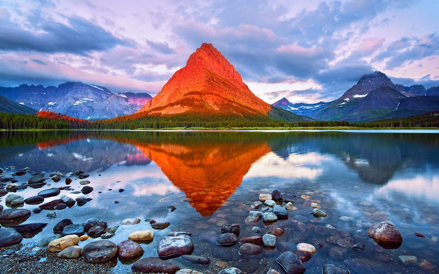 A mountain is transformed in to a glowing red beacon as the sun’s rays break through the clouds at sunrise. Harry Litchman captured the image at Grinnell Peak in Glacier National Park, Montana, America.