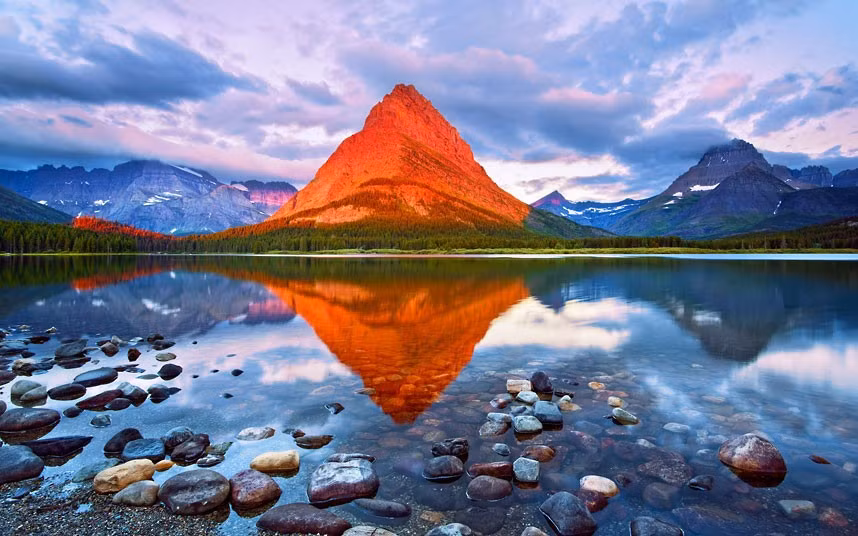 A mountain is transformed in to a glowing red beacon as the sun’s rays break through the clouds at sunrise. Harry Litchman captured the image at Grinnell Peak in Glacier National Park, Montana, America.