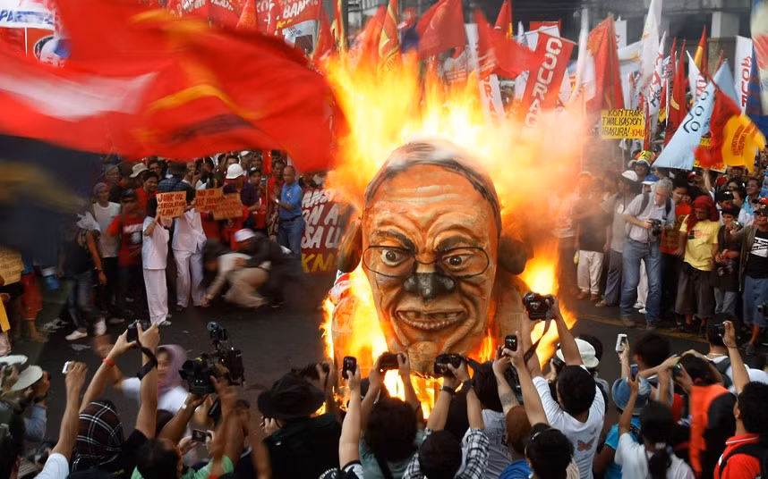 Protesters burn an effigy of Philippine President Benigno Aquino during a rally near the Presidential Palace in Manila