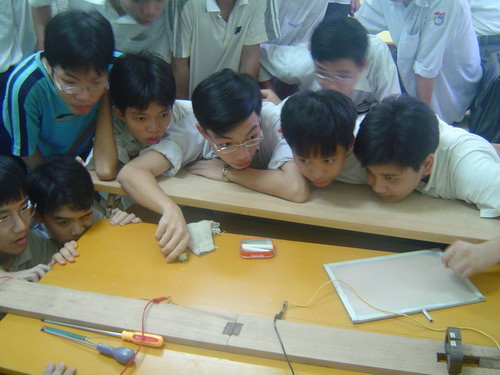 Học sinh đang quan sát thí nghiệm với dụng cụ thí nghiệm do giáo viên tự tạo.