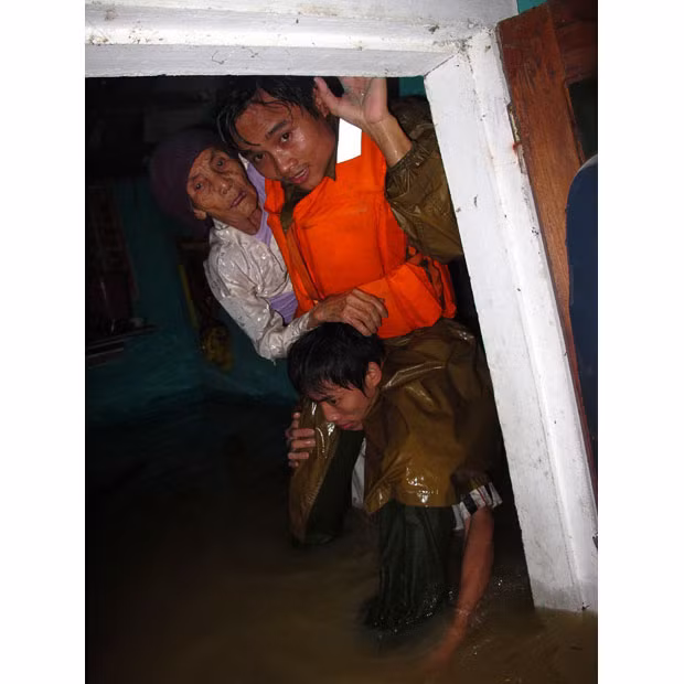 Rscuers help an elderly woman from her flooded home in Ha Tinh province, Vietnam