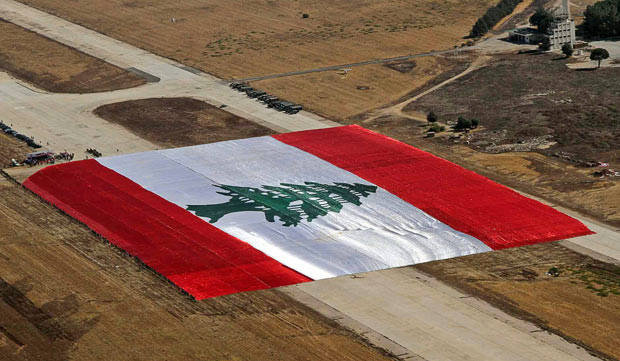 Những hình ảnh ấn tượng trong tuần ảnh 11 An aerial view taken from a helicopter shows the largest national flag in the world, at the Lebanese Air Force Base in Rayak, Bekaa valley. The Guinness Book of Records attempt was made to mark the 65th anniversary of the Lebanese Army. The flag is 65,650 square metres and the area of the cedar on the record-breaking flag is 10,452 square metres, a reference to Lebanon’s area of 10,452 square kilometres The flag, measuring 325 meters in length and 202 meters in width