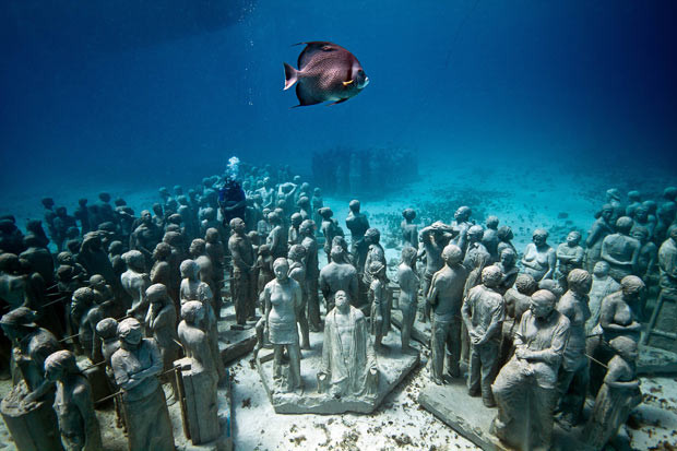 Những hình ảnh ấn tượng trong tuần ảnh 17 A fish swims past life-sized statues on the sea bed underwater at Cancun and Isla Mujeres National Marine Park in Mexico. British artist Jason de Caires Taylor, 36, from Cantebury, Kent, has created an artificial reef supporting marine life deep underwater - made from sculptures of real members of the public