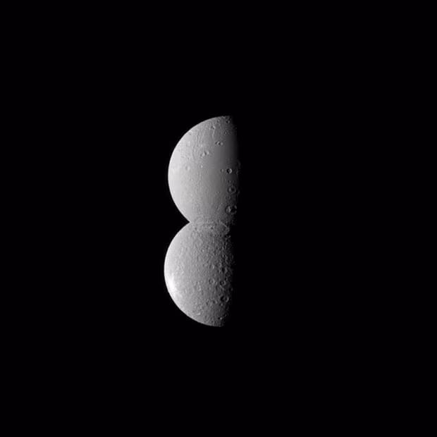 Two of Saturn’s moons - Rhea (bottom) and Dione (top) - appear conjoined in this Cassini spacecraft image. Dione is actually closer to the spacecraft here, but the reflection of the sun and a large crater at its south pole appears to make it blend seamlessly with Rhea. The newly-released image was taken July 27, 2010 at a distance of approximately 1.1 million kilometres (688,000 miles) from Dione and 1.6 million kilometres (994,000 miles) from Rhea