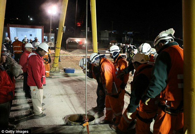 Escape hatch: Mine workers and government officials look into the hole as the rescue capsule is lowered into the mine Read more: http://www.dailymail.co.uk/news/article-1320045/CHILEAN-MINERS-RESCUE-Back-dead-69-days-trapped-underground.html#ixzz12HusOVrQ