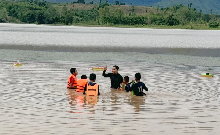 Lớp dạy bơi được tổ chức tại một hồ nước, có căng dây và phao xung quanh.