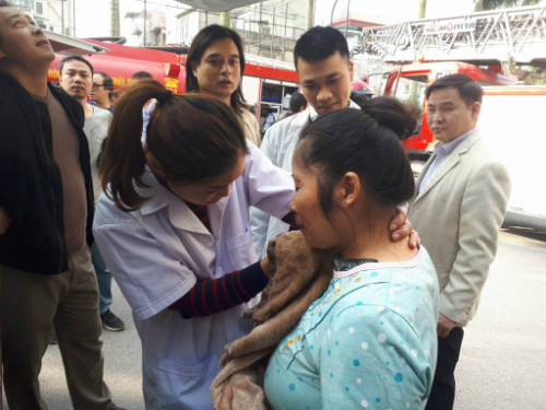 Nhân viên y tế chăm sóc người dân được cảnh sát giải cứu từ vị trí phát hoả. Ảnh: VnExpress