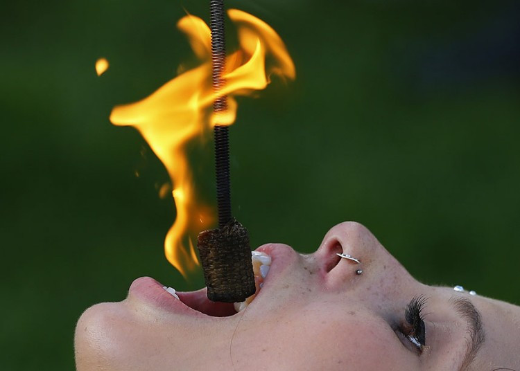 Street performer Kristin Decker performs a fire-eating act before the opening ceremonies for the 2013 Presidents Cup golf tournament in Columbus.