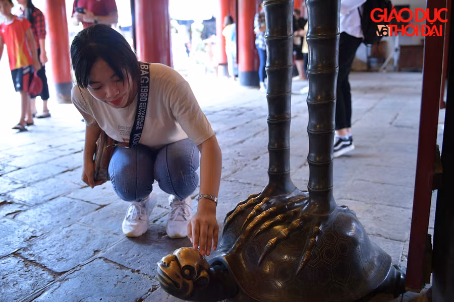 Các sĩ tử được thoải mái sờ đầu rùa đồng cõng hạc đặt ở ngoài chính điện